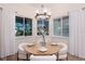 Dining room with a round table, modern chandelier, and large windows overlooking the backyard at 3800 Carupano Ct, Punta Gorda, FL 33950