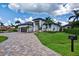 A modern home exterior with a manicured lawn, stone driveway, lush tropical landscaping, and a stately entrance at 3800 Carupano Ct, Punta Gorda, FL 33950