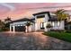 Stunning exterior elevation of a modern home featuring a three-car garage and meticulous landscaping at sunset at 3800 Carupano Ct, Punta Gorda, FL 33950