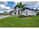 A modern home exterior with lush landscaping, palm trees, manicured lawn, and a well-lit entryway at 3800 Carupano Ct, Punta Gorda, FL 33950