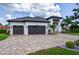 Beautiful exterior of home with stone driveway and a three-car garage in a tropical landscape at 3800 Carupano Ct, Punta Gorda, FL 33950