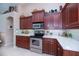 Well-equipped kitchen with stainless steel appliances, white countertops, and cherry wood cabinets at 3824 Dominic St, North Port, FL 34288