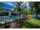 View of screened pool area, enhanced by palm trees and tropical landscaping, in a private backyard at 3824 Dominic St, North Port, FL 34288