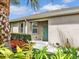 Inviting front entrance with a colorful door, vibrant flowers, and lush tropical landscaping at 4180 Lenox Blvd, Venice, FL 34293