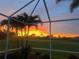 Inviting back porch view of a stunning sunset over lush landscaping and the golf course at 4567 Whispering Oaks Dr, North Port, FL 34287