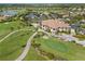 An aerial view of the clubhouse, tennis courts, golf course, and parking lot at 4567 Whispering Oaks Dr, North Port, FL 34287