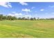 View of green golf course with golfers playing under a blue, cloudy sky at 4567 Whispering Oaks Dr, North Port, FL 34287