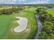 An aerial view of the lush green golf course with a sand trap and a cart path at 4567 Whispering Oaks Dr, North Port, FL 34287
