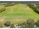 An aerial view of the driving range, golf course, and surrounding trees at 4567 Whispering Oaks Dr, North Port, FL 34287
