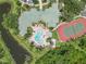 Aerial view of a community, featuring a pool, tennis court, lush landscaping, and lakeside scenery at 5146 Northridge Rd # 305, Sarasota, FL 34238