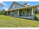 Charming green home featuring a covered front porch with rocking chairs and white columns at 5242 Blackjack Cir, Punta Gorda, FL 33982