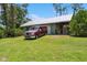 Exterior view of house and detached garage with green lawn in front and a vehicle parked at 5242 Blackjack Cir, Punta Gorda, FL 33982