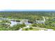 An aerial view of the white house with a paver driveway, two car garage, and luscious green trees at 576 Mcdill Dr, Port Charlotte, FL 33953
