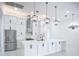 Modern white kitchen with island, stainless steel appliances, and designer lighting at 576 Mcdill Dr, Port Charlotte, FL 33953