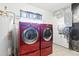 Laundry room showcasing side by side red washer and dryer and tile flooring at 6196 Mayberry Ave, North Port, FL 34287