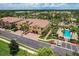 Aerial view of condo building featuring a red tile roof, a pool, lush landscaping and multiple parking spaces at 8098 Moonstone Dr # 17-203, Sarasota, FL 34233