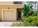 Townhome entrance featuring a large garage, dark wood door, and decorative tropical landscaping at 8098 Moonstone Dr # 17-203, Sarasota, FL 34233