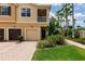 Townhome with a multi-car garage, second-floor balcony, and professionally maintained lush tropical landscaping at 8098 Moonstone Dr # 17-203, Sarasota, FL 34233
