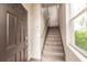 Carpeted staircase with a dark wood door and natural light, inviting ascent to the upper level of the home at 8098 Moonstone Dr # 17-203, Sarasota, FL 34233
