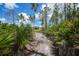 View of home from a wooded sandy driveway amid Florida foliage under a blue sky with scattered clouds at 8312 Acorn Blvd, Punta Gorda, FL 33982