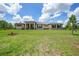 Expansive single-story home featuring a metal roof, neutral stucco, stone accents, and a large green lawn under a blue sky at 8312 Acorn Blvd, Punta Gorda, FL 33982