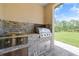 Outdoor kitchen featuring built-in appliances and a stone backsplash, ideal for outdoor entertaining and grilling at 8312 Acorn Blvd, Punta Gorda, FL 33982