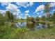 Scenic pond reflecting the blue sky and puffy clouds in the backyard creating a peaceful outdoor space at 8312 Acorn Blvd, Punta Gorda, FL 33982