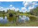 Scenic view of a pond reflecting a home and the sky with white puffy clouds at 8312 Acorn Blvd, Punta Gorda, FL 33982