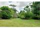 Lush green backyard with mature trees and foliage, creating a private and serene outdoor space at 875 Bayshore Dr, Englewood, FL 34223