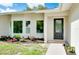 Home's entrance with leaded glass door and colorful flower beds at 875 Bayshore Dr, Englewood, FL 34223