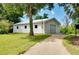 Exterior view of the garage, featuring a roll-up door, gravel driveway, and a well-maintained yard at 875 Bayshore Dr, Englewood, FL 34223