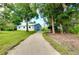 Exterior view of the garage, featuring a roll-up door, gravel driveway, and surrounded by lush greenery at 875 Bayshore Dr, Englewood, FL 34223