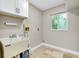 Bright laundry room with utility sink, cabinets, and a window for natural light at 875 Bayshore Dr, Englewood, FL 34223
