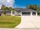 Exterior view of home with well-manicured lawn, three-car garage and circular driveway at 10055 Franklin Dr, Englewood, FL 34224
