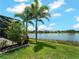 View of backyard with mature palm trees and tropical landscaping and a serene lake in the background at 10131 Winding River Rd, Punta Gorda, FL 33950