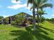 Spacious backyard with a covered patio, lush landscaping, palm trees, and a scenic view of the lake at 10131 Winding River Rd, Punta Gorda, FL 33950