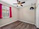 Bedroom featuring red curtains, ceiling fan, wood-look floors, and modern lighting at 10131 Winding River Rd, Punta Gorda, FL 33950
