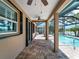 Covered patio with brick flooring leading to a screened lanai and a swimming pool overlooking the lake at 10131 Winding River Rd, Punta Gorda, FL 33950