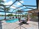 A view of the backyard pool, screened-in patio, and lake with bright sunshine at 10131 Winding River Rd, Punta Gorda, FL 33950