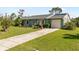 Charming single-story home with green exterior, manicured lawn, and attached garage at 11068 Jacqueline Ave, Englewood, FL 34224