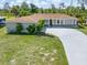 Exterior front view featuring a lush green lawn, driveway, and a home with neutral paint at 123 Annapolis Ln, Rotonda West, FL 33947