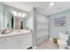 Light-filled bathroom with blue walls featuring a shower with striped curtain, vanity, and a decorative shell collection at 12425 Ghiberti Cir # 101, Venice, FL 34293