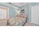 Calming bedroom features a palm tree wall art, soft blue walls, and a comfy floral patterned bedspread, creating a tranquil vibe at 12425 Ghiberti Cir # 101, Venice, FL 34293