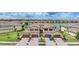 An exterior view showcases tan-colored homes with red-tiled roofs, landscaped grounds, and a serene pond in the background at 12425 Ghiberti Cir # 101, Venice, FL 34293