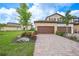 Charming villa with a two-car garage, colorful landscaping, and a brick-paved driveway, complemented by a lush green lawn at 12425 Ghiberti Cir # 101, Venice, FL 34293