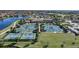 An aerial view features multiple tennis and pickleball courts with players, surrounded by lush greenery and a nearby lake at 12425 Ghiberti Cir # 101, Venice, FL 34293