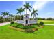 Grand entrance to Heritage Landing features lush landscaping, a decorative gatehouse, and swaying palm trees at 14684 Cherry Blossom Way, Punta Gorda, FL 33955