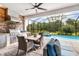 Outdoor kitchen featuring a built-in grill, dining area, and a view of the sparkling swimming pool and lush landscaping at 14684 Cherry Blossom Way, Punta Gorda, FL 33955