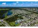 Aerial view showcases the community's homes, amenities, a beautiful lake, and a community pool under a bright, sunny sky at 17032 Yellow Pine St, Wimauma, FL 33598