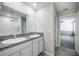Bright bathroom featuring tiled floors, granite countertops, double vanity and tiled shower with glass door at 17032 Yellow Pine St, Wimauma, FL 33598